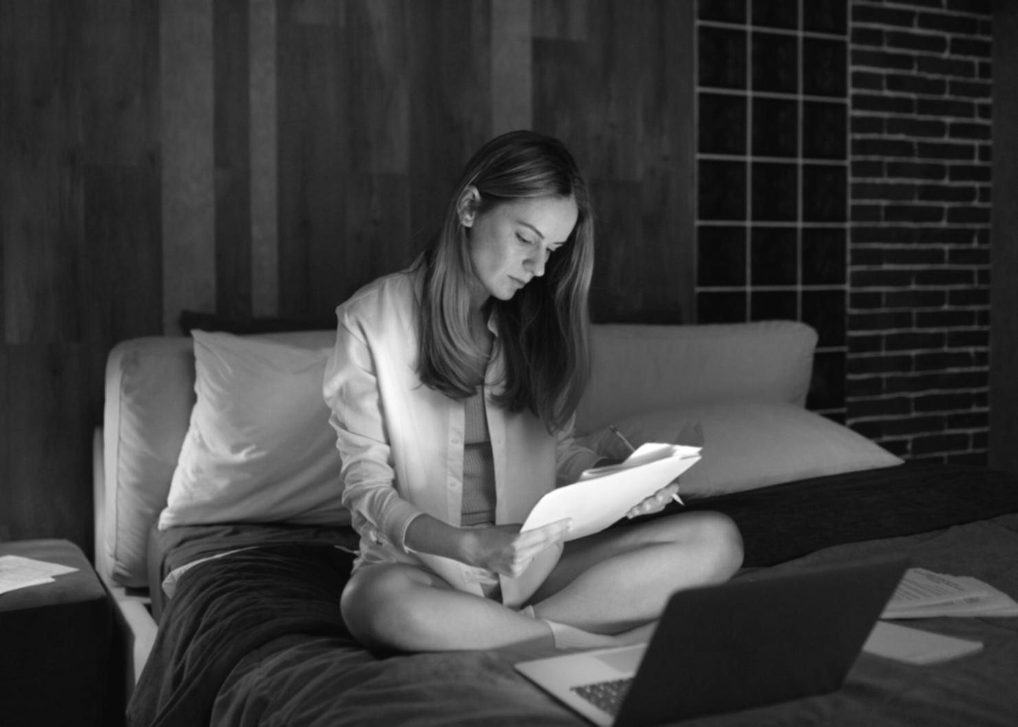 Person arbeitet konzentriert am Laptop mit Notizbuch und Finanzunterlagen